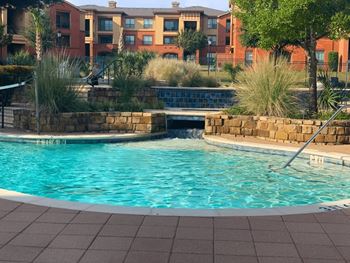 A swimming pool surrounded by a brick wall and a building in the background.